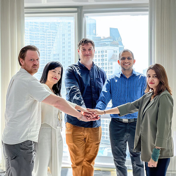 5 employees joining hands in unison as a team